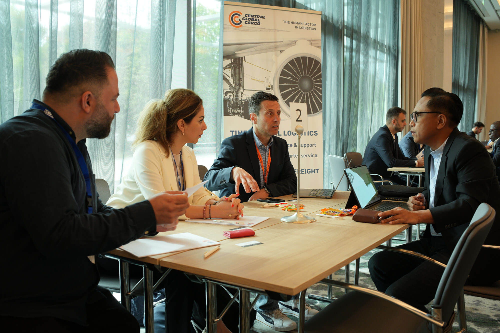 Members meeting around a table beside a sponsor stand